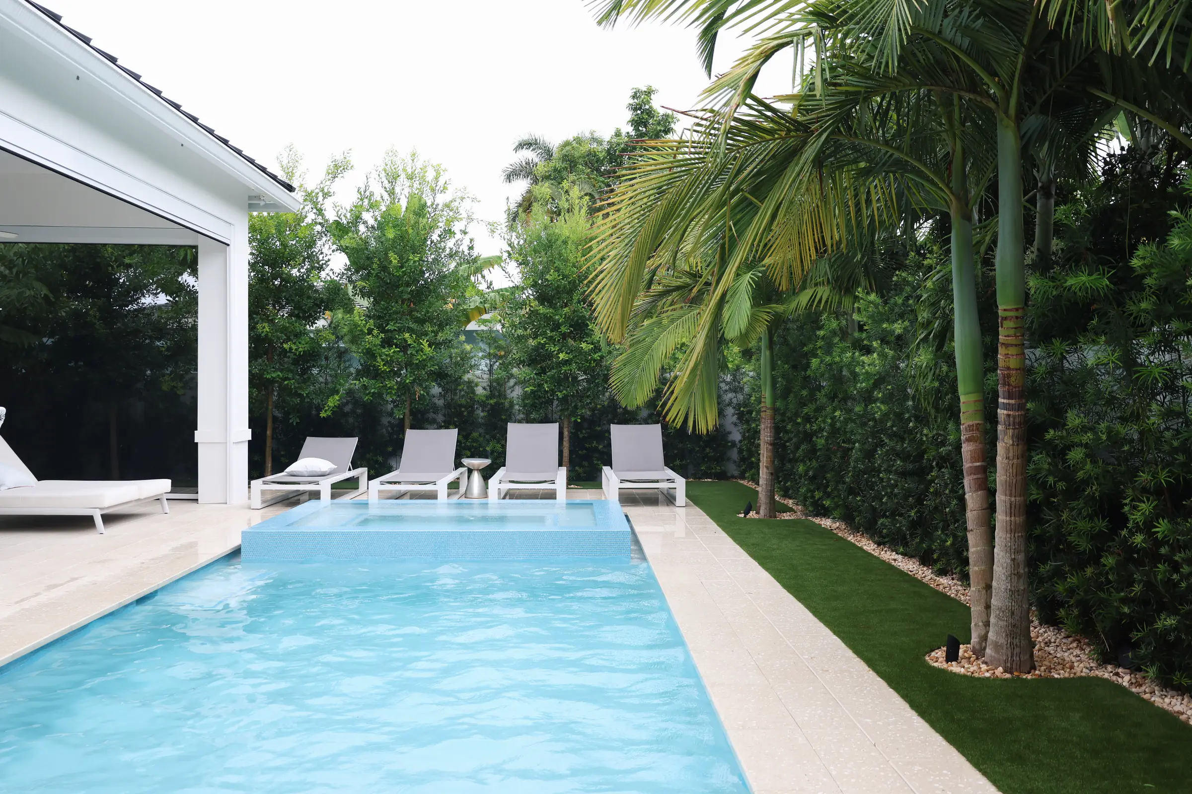 Pool, loungers and palms toward cabana